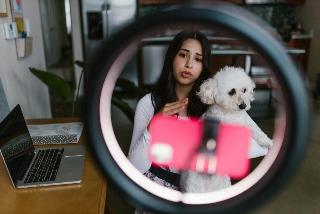 Young woman vlogging with her dog at home, creating content indoors.